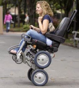 Outside at a park a woman is in an iBot chair that is on two small wheels only smiling